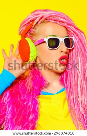 Glamorous modern DJ girl wearing bright clothes, headphones and bright dreadlocks. Disco, party. Bright fashion.