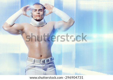 Technologies of the future, man of the future. Handsome muscular man with futuristic make-up in the headphones standing on a luminous transparent background.