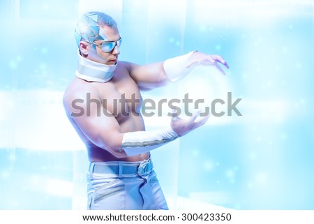 Technologies of the future, man of the future. Handsome muscular man with futuristic make-up wearing glasses stands on a luminous transparent background and touches something virtual.