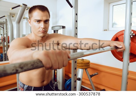 Handsome muscular man with weight training equipment in a gym. Sports, bodybuilding. Healthy lifestyle.