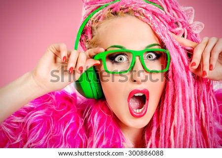 Trendy DJ party girl in bright clothes, headphones and with bright pink dreadlocks. Disco, party. Show business. Bright fashion.