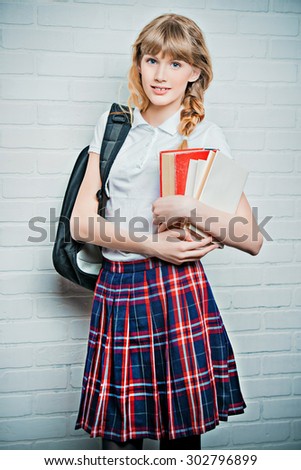 Pretty teen girl wearing school uniform and school bag. Education. Studio shot.