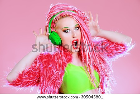 Trendy DJ party girl in bright clothes, headphones and with bright pink dreadlocks. Disco, party. Show business. Bright fashion.