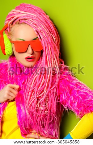 Modern party girl DJ in bright clothes, headphones and with bright dreadlocks. Disco, party. Show business. Bright fashion.