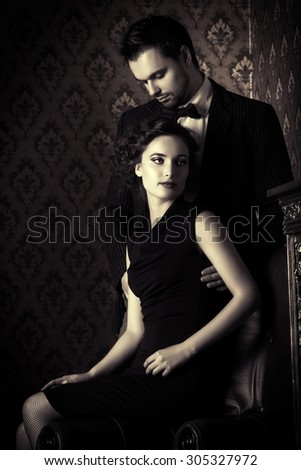 Black-and-white photo of a beautiful couple in elegant evening clothes in classic vintage apartments. Glamour, fashion. Love concept.