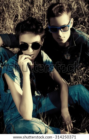 Attractive young couple wearing jeans clothes lying relaxed on a grass. Fashion shot.