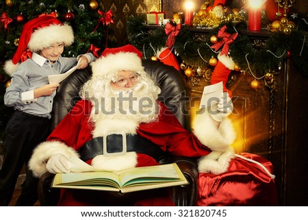 Little boy and Santa Claus reading letters from children. They are at home, decorated for Christmas. Santa\'s mail.