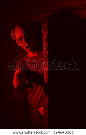 Frightening bloody zombie man in blood-red light. Halloween.