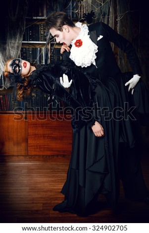 Gorgeous couple of vampires dressed in medieval clothing dancing in the old abandoned castle. Halloween. Carnival.