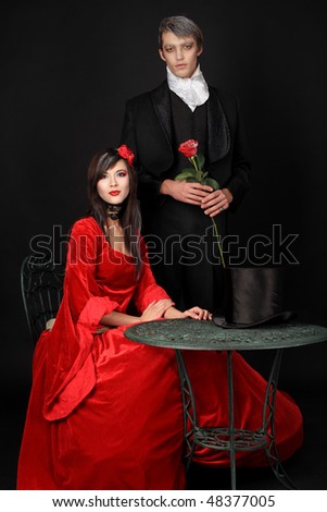 Portrait of a beautiful couple in medieval costumes with vampire style make-up. Shot in a studio.