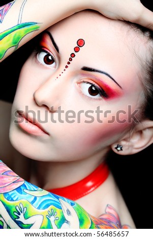 Stylish young woman with colored tattoo on her hand. Shot in a studio.