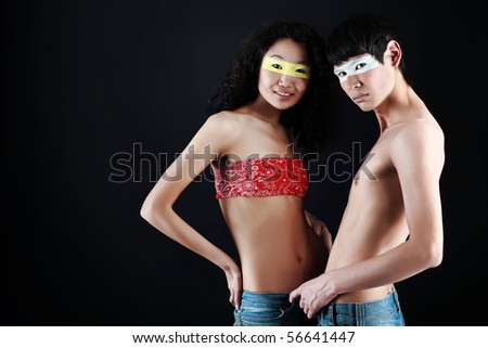 Shot of a couple of young people with painted eyes posing together over black background.