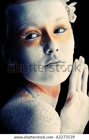 Portrait of an artistic woman painted with white and bronze colors, over black background. Body painting project.