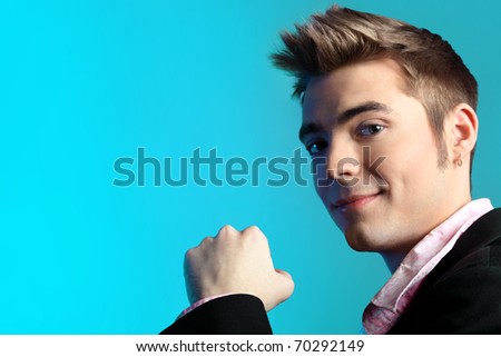 Young man dressed in rock'n'roll style, posing over blue background.