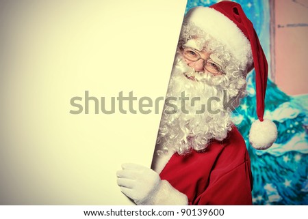 Santa Claus holding white board over Christmas background.