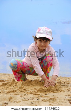 Child on river shore play in sand