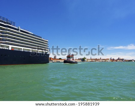 giant cruise ship for the transportation of passengers pulled by a tugboat out of the marina, Venice, Italy