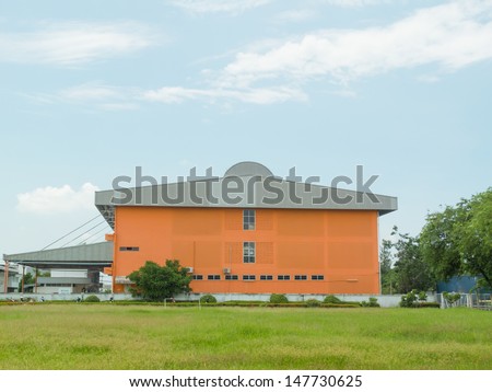 Orange small Office Building with Plant Arrangements Behind lawn.