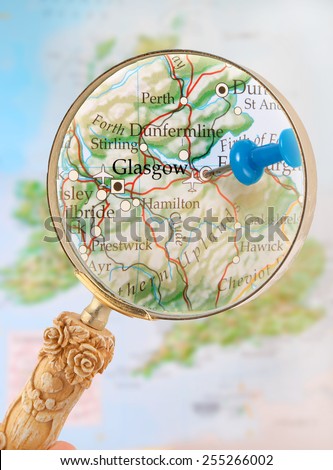 Blue tack on map  with magnifying glass looking in on Glasgow, Scotland, United Kingdom