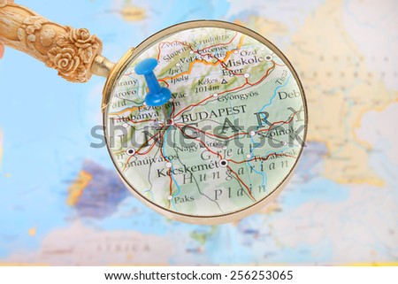 Blue tack on map of Europe with magnifying glass looking in on Budapest, Hungary