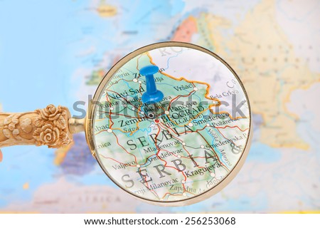 Blue tack on map of Europe with magnifying glass looking in on Belgrade, Serbia