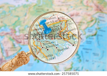 Blue tack on map of the world with magnifying glass looking in on Dhaka, Bangladesh