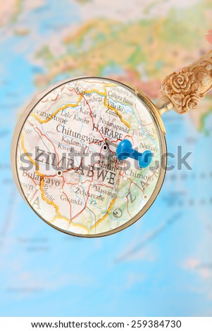 Blue tack on map of Africa with magnifying glass looking in on Harare, Zimbabwe,