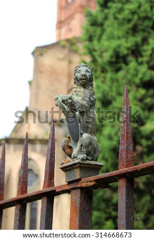 Old and rusty wrought iron fence with green lion metal decoration in Bologna, Italy