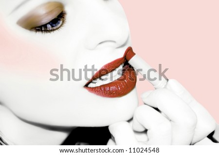 desaturated image with color enhanced on lips and eyes .... woman applying lipstick in an orange hue