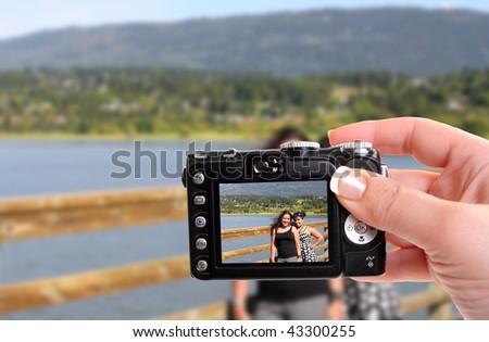 Woman taking a snapshot of two young sisters or friends of Indian ethnic background by the lake in Salmon Arm, British Columbia, Cananda
