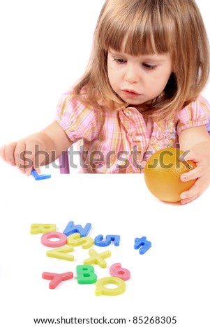 Young girl holding an orange playing with letters and numbers for early childhood development