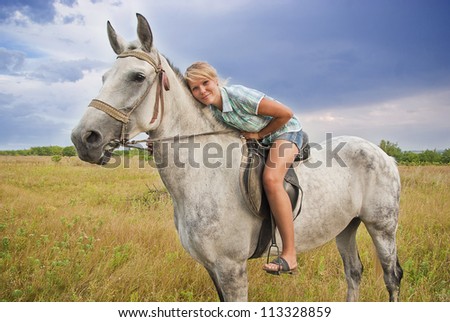 Young adult women ridind on gray horse on meadow, East Europe