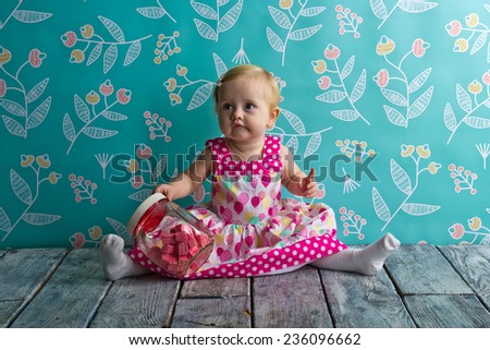 Little girl sitting on the wooden floor with candy jar
