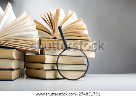 Composition with hardback books and magnifying glass. on the table. Open book, fanned pages. Back to school, copy space. Education background.