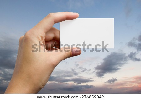 Hands holding a white business visit card, gift, ticket, pass, present closeup on sky background. Copy space