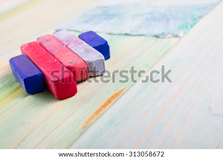 Pastel crayons and pigment dust on old wooden background. Copy space, education background.