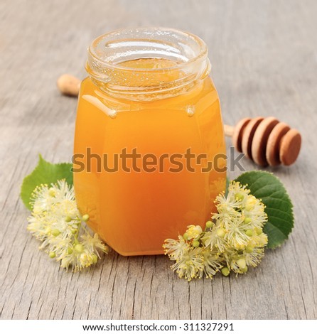 Honey with linden flowers on wooden texture.