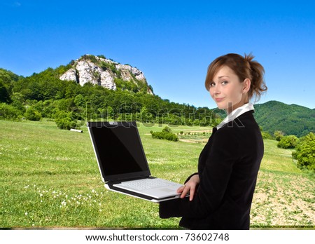 Businesswoman working on laptop computer, in nature
