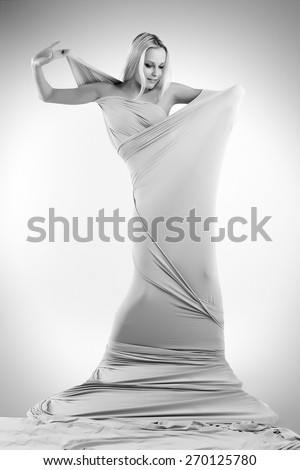 Art photo of a women silhouette breaking through the fabric.  Black and white photo
