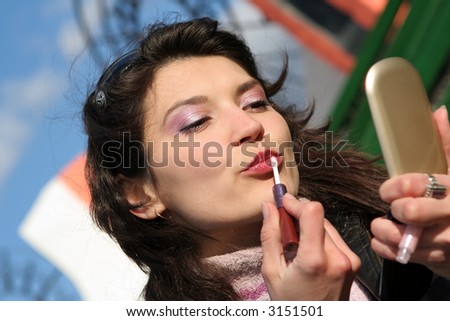 A closeup of a woman putting on lip liner.