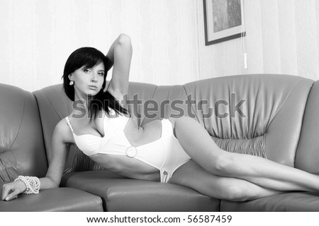 Glamour model poses on the sofa. Black and white photo.