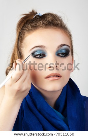Portrait of the beautiful woman with make-up brushes near attractive face.