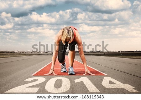 Female sprinter prepares for the start on an airport runway.In the foreground perspective view of  letters 2014.