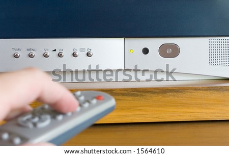 Close-up of various buttons/LED light on a TV and with a blurred remote control in the foreground
