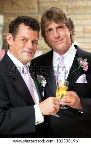 Handsome gay couple give champagne toast at their wedding reception.