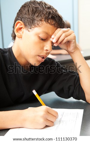 Handsome school boy struggling to finish a test in class.