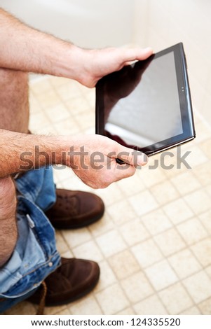 Man using a generic tablet PC while he goes to the bathroom.