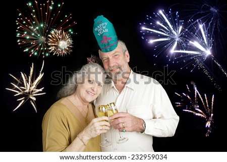 Beautiful senior couple celebrating a Happy New Year with a champagne toast, while fireworks go off in the background.