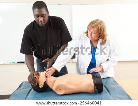 Adult student learning CPR from a medical doctor, using a state-of-the-art dummy.