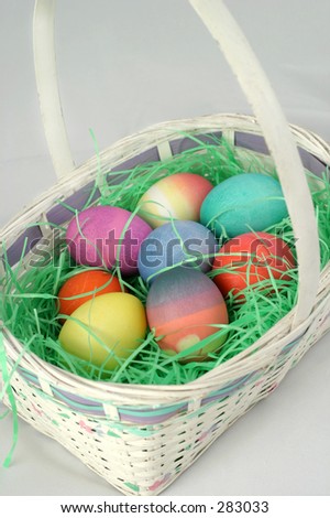 A white Easter basket, filled with colorful Easter eggs.